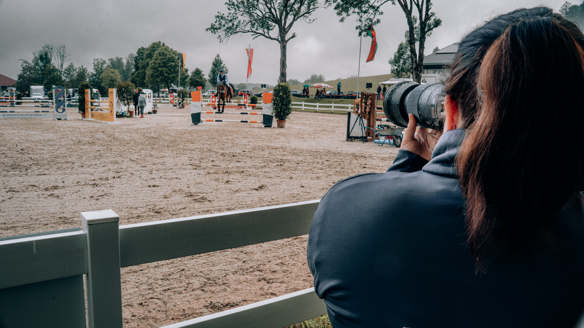 Professionelle Turnierfotografin fotografiert einen Springreiter mit Pferd während eines Reitturniers – hochwertige Pferdefotografie und Sportfotografie bei Outdoor-Event